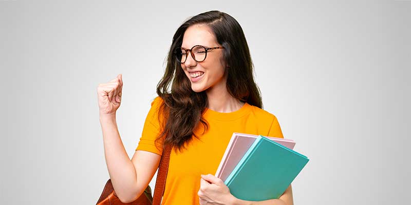 Woman holding books and clenches her fist and shows her biceps - success as an inlingua licensee