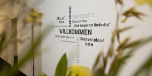 Eingang bei inlingua Ostschweiz. Weisse Wand mit "Willkommen" in verschiedenen Sprachen.