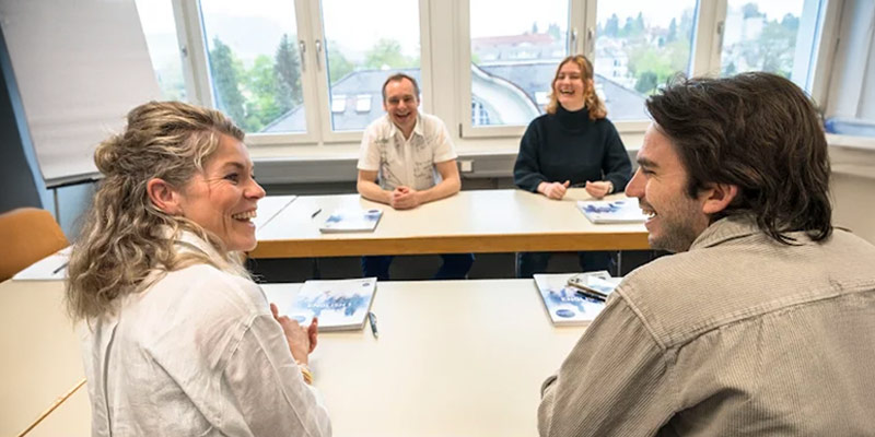 Classroom with learners chatting and laughing with each other.