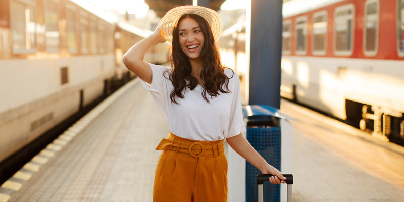 Woman at the trainstation wearing a hat and going on a language journey
