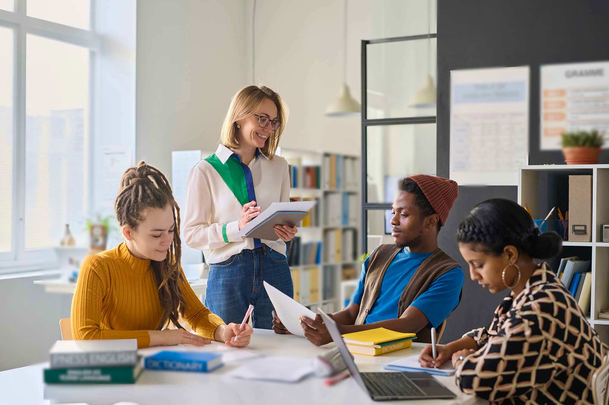 Language trainer giving feedback to a small group of learners working together in a classroom