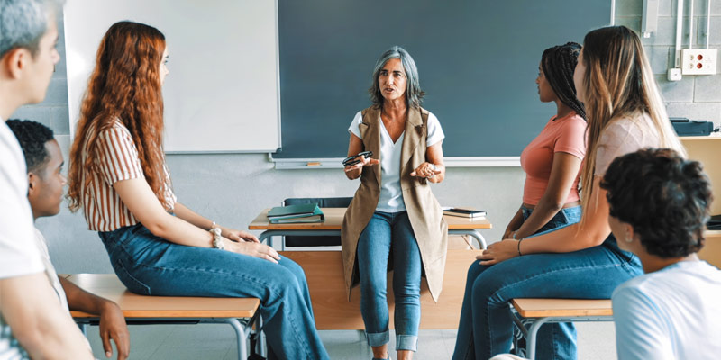 Language trainer interacting with a group of learners during a classroom discussion