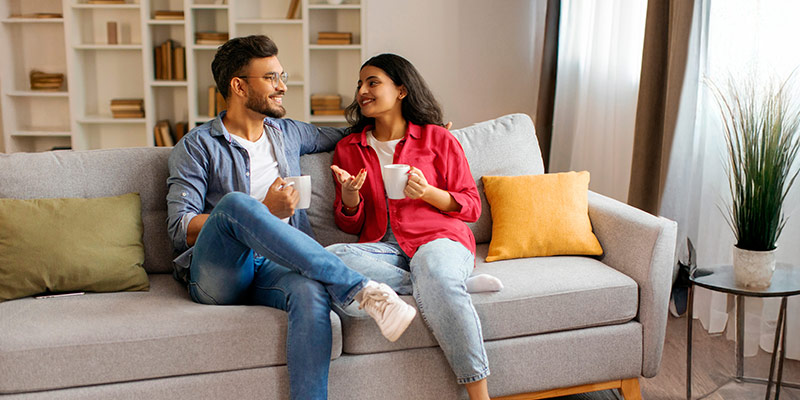 Two person having an emotional discussion on a sofa and drinking tea