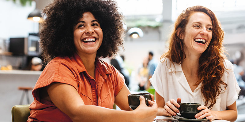 Two happy women drinking coffee and having a conversation