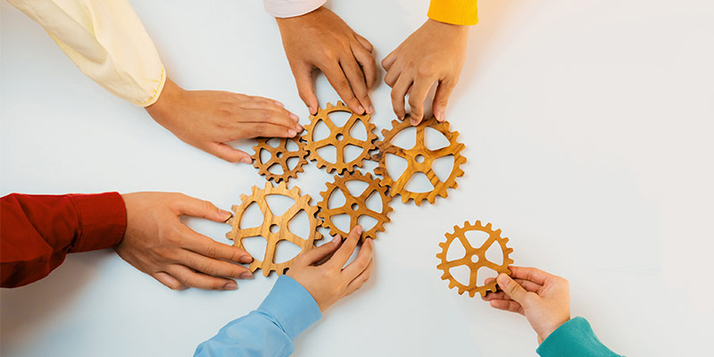 Hands of different people are connected by gears