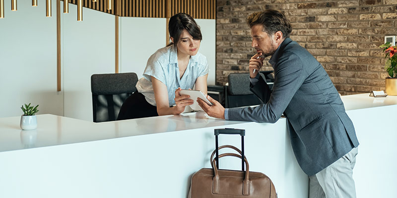 Hotel guest checking details on an iPad with a receptionist.