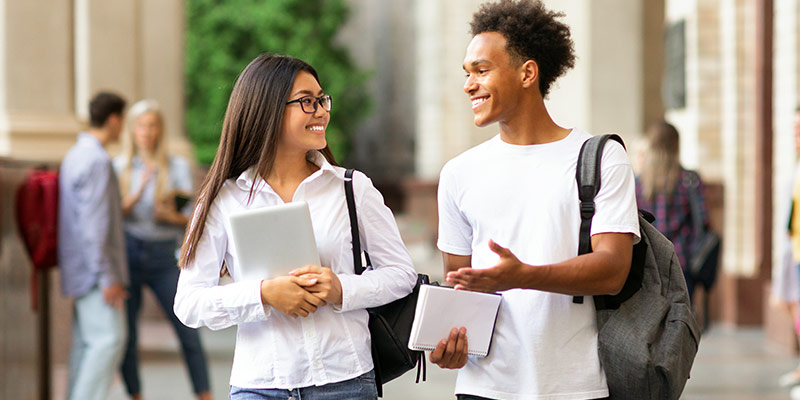 Learners confidently communicating in a real-life setting while carrying books and backpacks