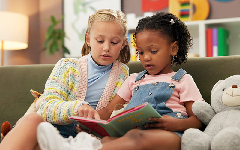 Two children exploring a storybook together, fostering early language learning development