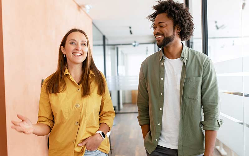 Two colleagues talking while walking through a modern office