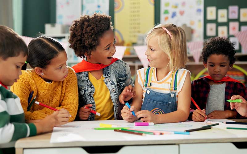 Children collaborating on a classroom activity, demonstrating natural language learning through social interaction and playful language acquisition