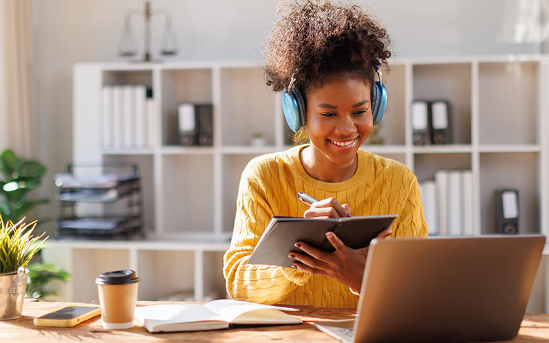 Language learner studying online and taking notes during a virtual lesson