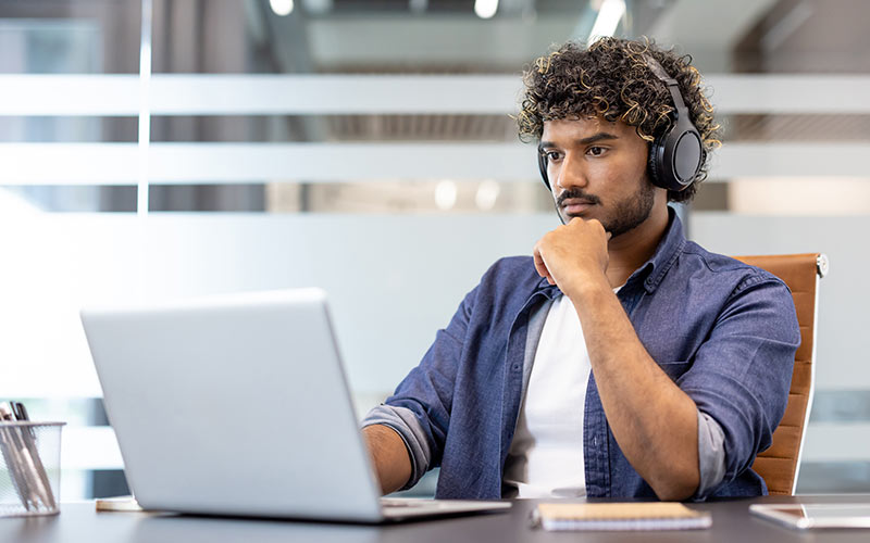 Learner completing an online language placement test with listening tasks on a laptop