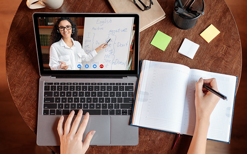Learner attending a live online language lesson and taking notes as part of a blended learning program