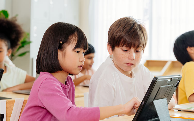 Children using a tablet together during a classroom learning exercise