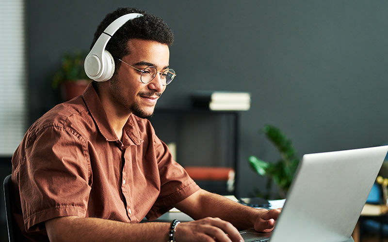 Learner using an online language learning platform with headphones and a laptop