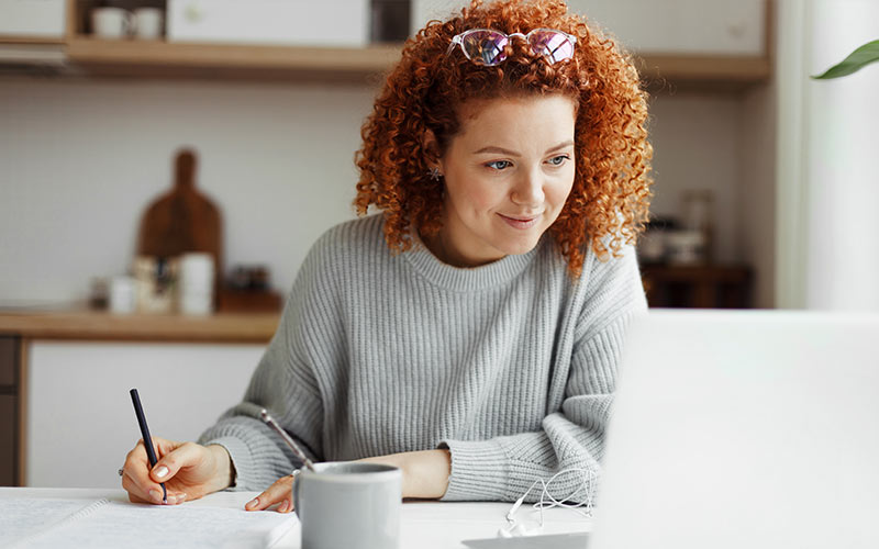 Learner studying a language independently at home using a laptop and notes