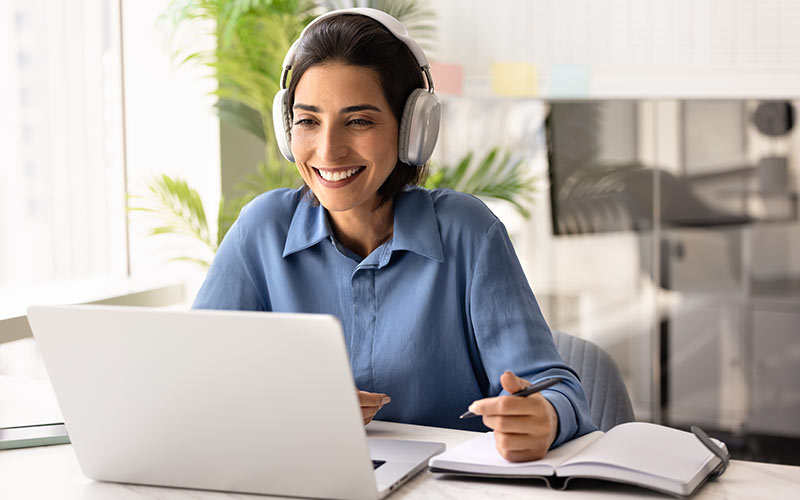Learner studying on a laptop at home and taking notes