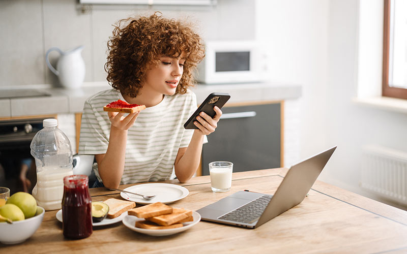 Learner using a smartphone over breakfast, illustrating how digital language practice can fit into everyday routines