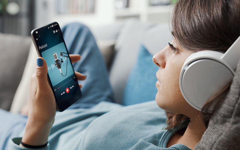 Learner listening to a podcast on her smartphone with headphones, an example of audio resources for language learning
